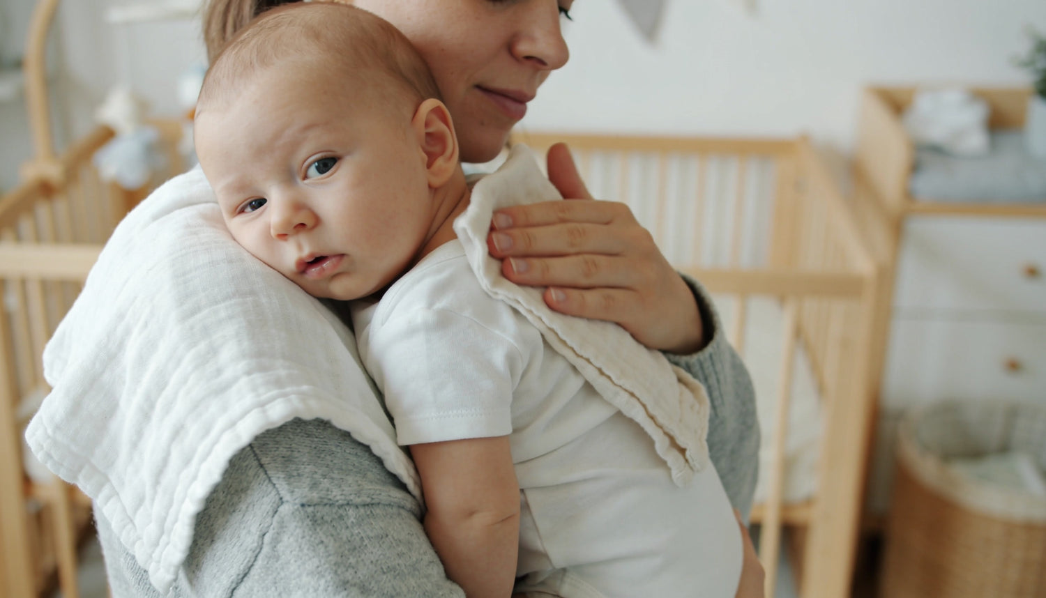 Forælder bøvser baby over skulderen med stofble